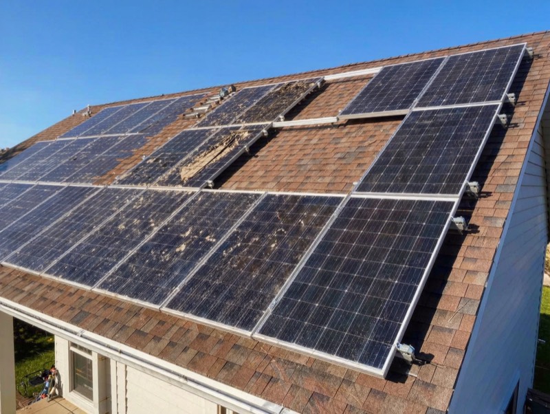 Solar panels on a roof with damaged and dirty panels and a missing row